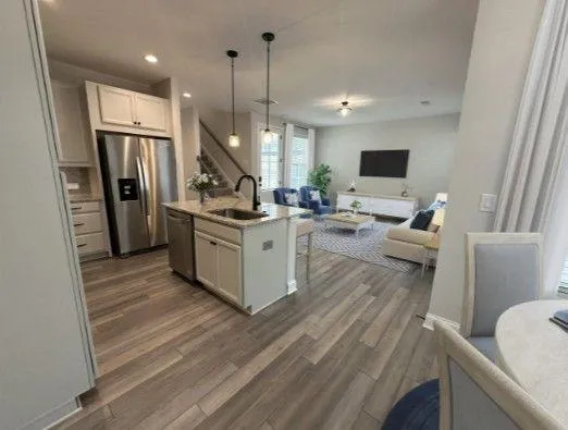 a kitchen with stainless steel appliances a stove a refrigerator a sink a oven with a dining table and chairs