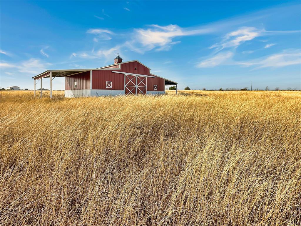 501 County Road 501 Blue Ridge, TX 75424 - Photo 3 of 27 Front elevation of the barn featuring red metal siding with white trim, double sliding barn doors, and a wide central entrance set on a concrete foundation.