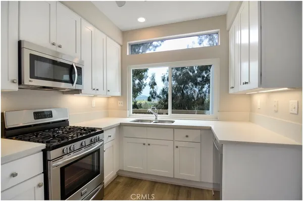 a kitchen with granite countertop a sink stainless steel appliances a window and a counter top space