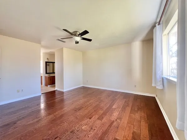 a view of empty room with wooden floor and fan