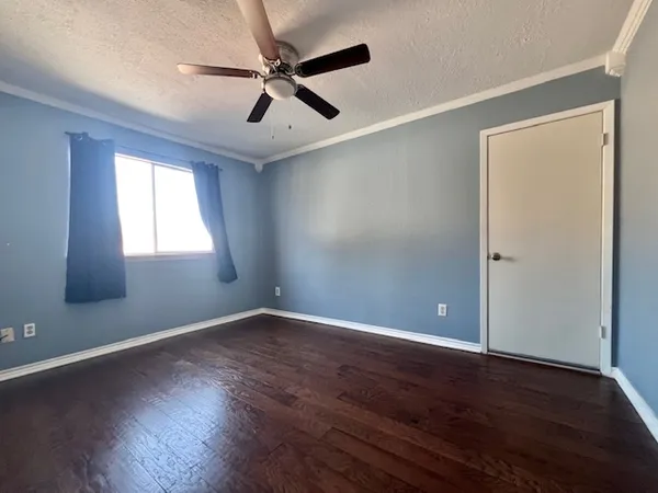 an empty room with wooden floor fan and windows