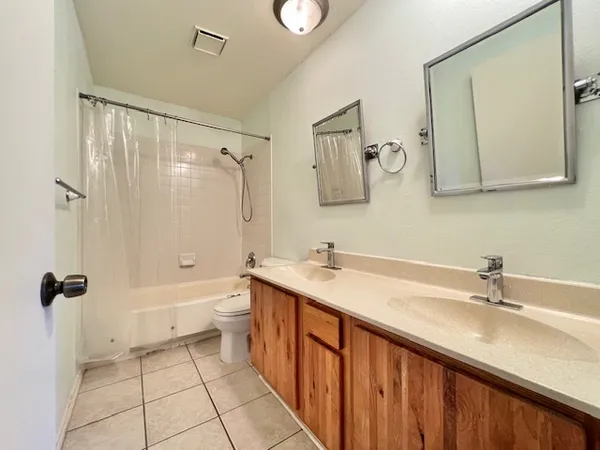 a bathroom with a double vanity sink toilet mirror and shower
