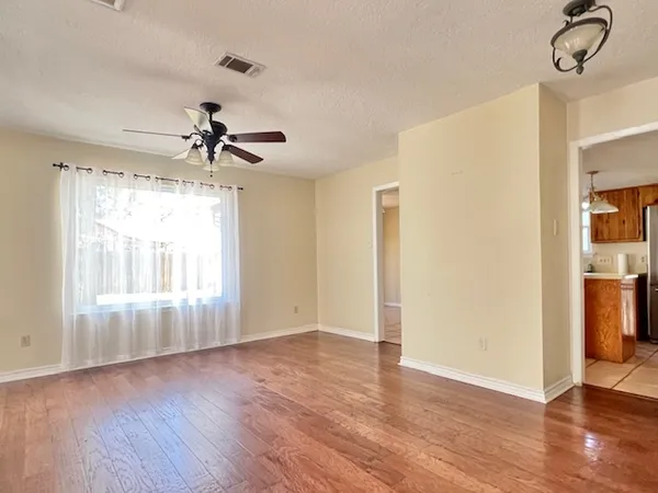 a view of empty room with wooden floor and fan