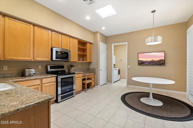 a kitchen with stainless steel appliances granite countertop a sink a stove a microwave a refrigerator cabinets and living room view