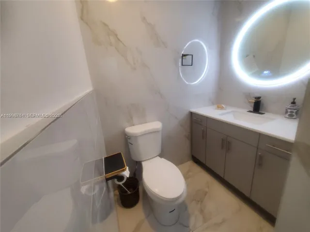 a bathroom with a toilet sink vanity tub and mirror