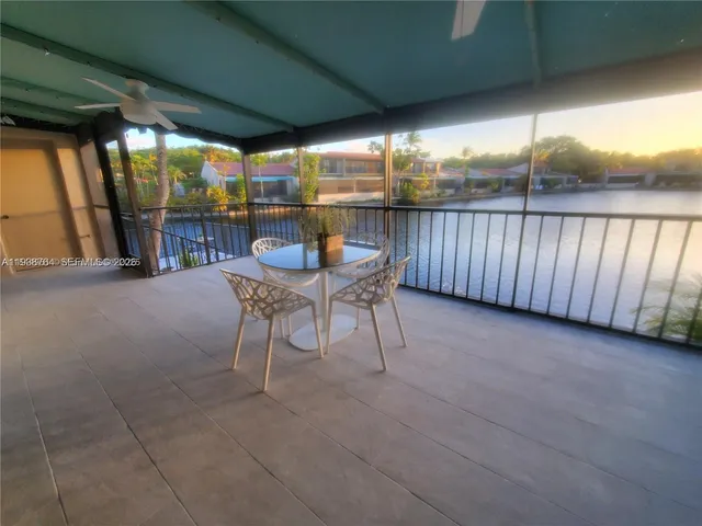 a view of a patio with table and chairs and floor to ceiling window with wooden fence