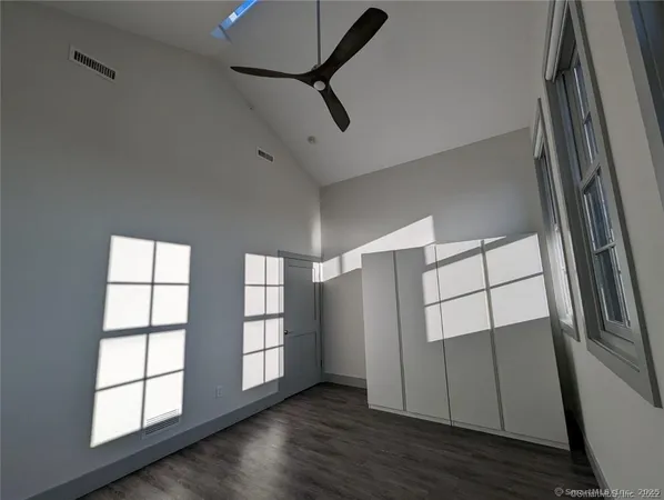 a view of an empty room with wooden floor and windows