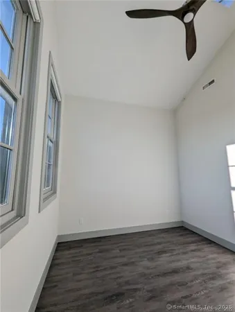 an empty room with windows and ceiling fan