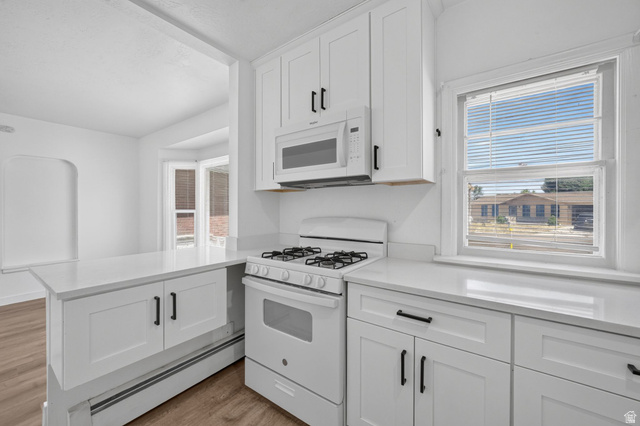 220 East Greenwood Avenue Midvale, UT 84047 - Photo 9 of 46 Bright kitchen featuring white shaker cabinetry, white countertops, a gas range, and an over-the-range microwave