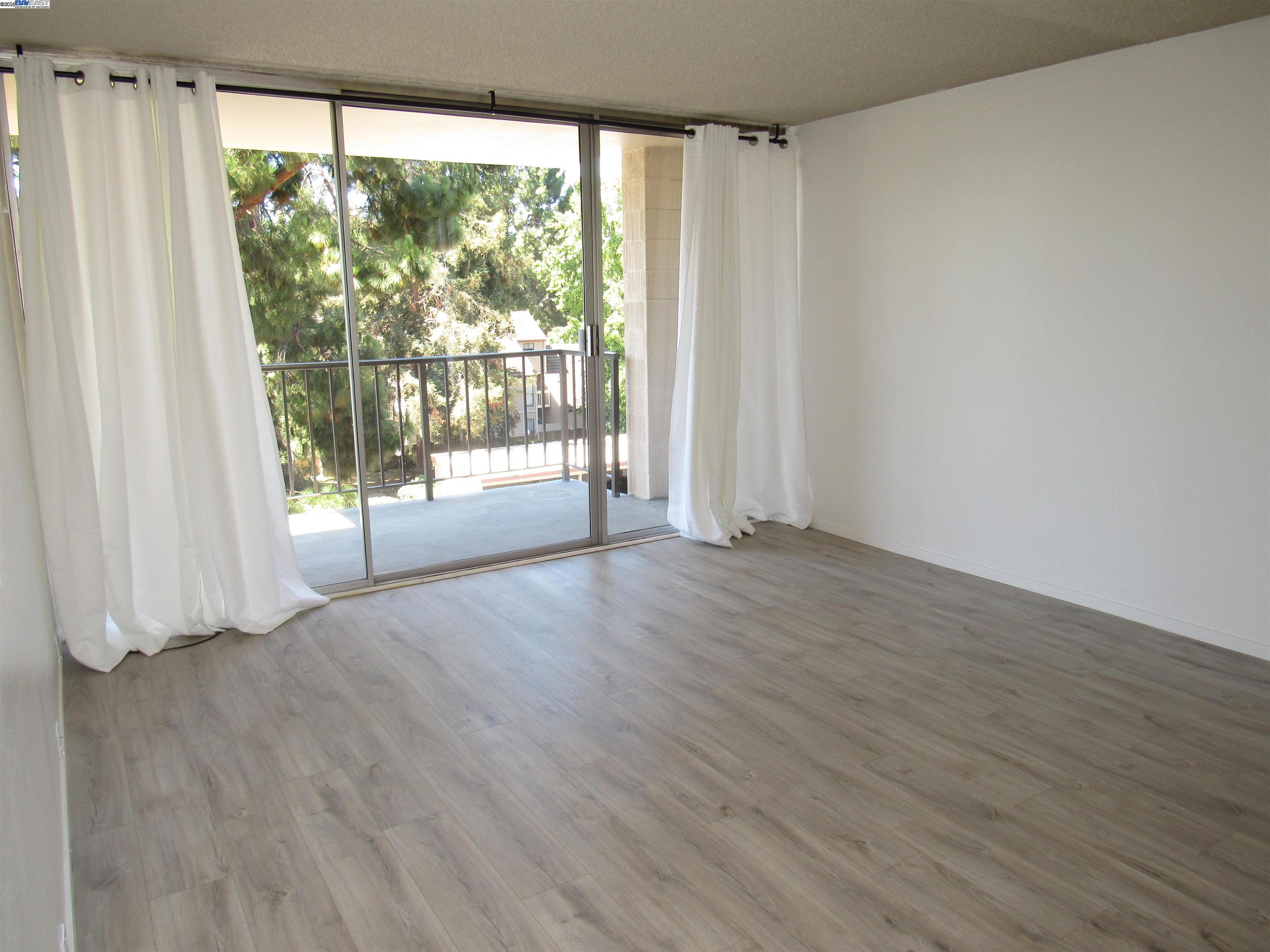 3909 Stevenson Boulevard, Unit 402 Fremont, CA 94538 - Photo 20 of 32 a view of an empty room with wooden floor and a window