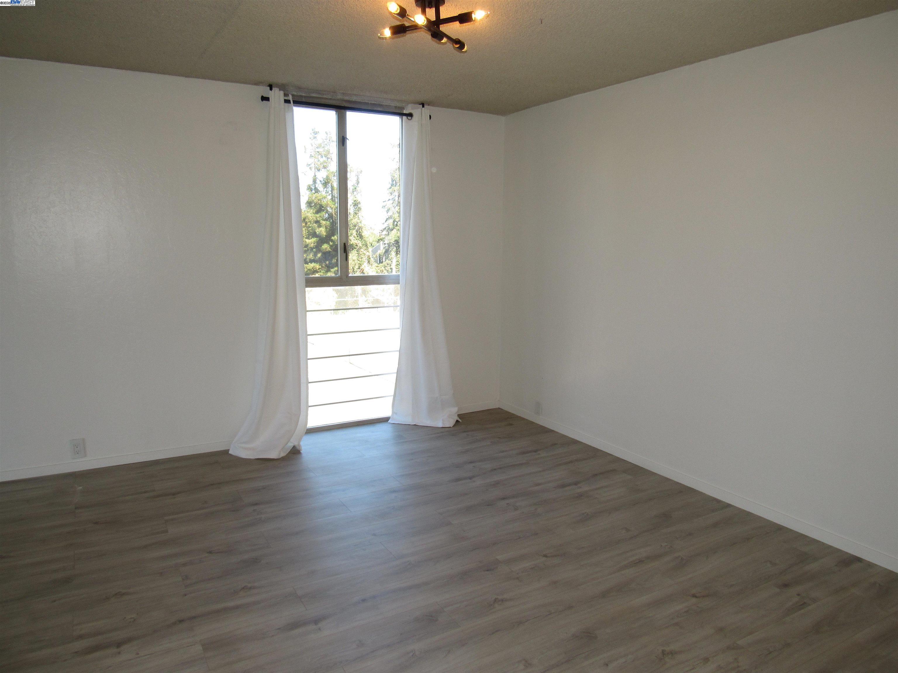3909 Stevenson Boulevard, Unit 402 Fremont, CA 94538 - Photo 10 of 32 a view of an empty room with wooden floor and a window