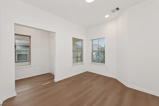 an empty room with wooden floor and windows