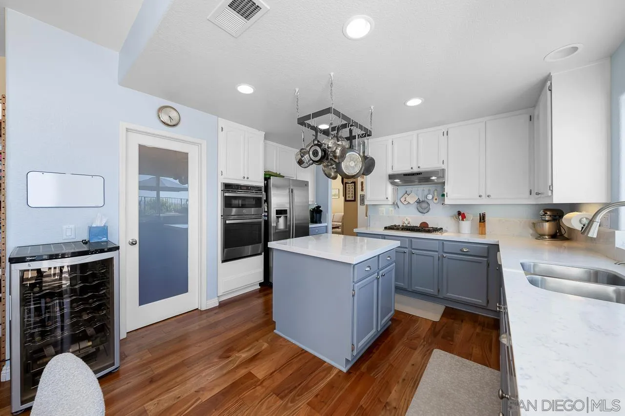 5114 Bella Collina Street Oceanside, CA 92056 - Photo 12 of 74 a large kitchen with stainless steel appliances granite countertop a lot of counter space and wooden floor