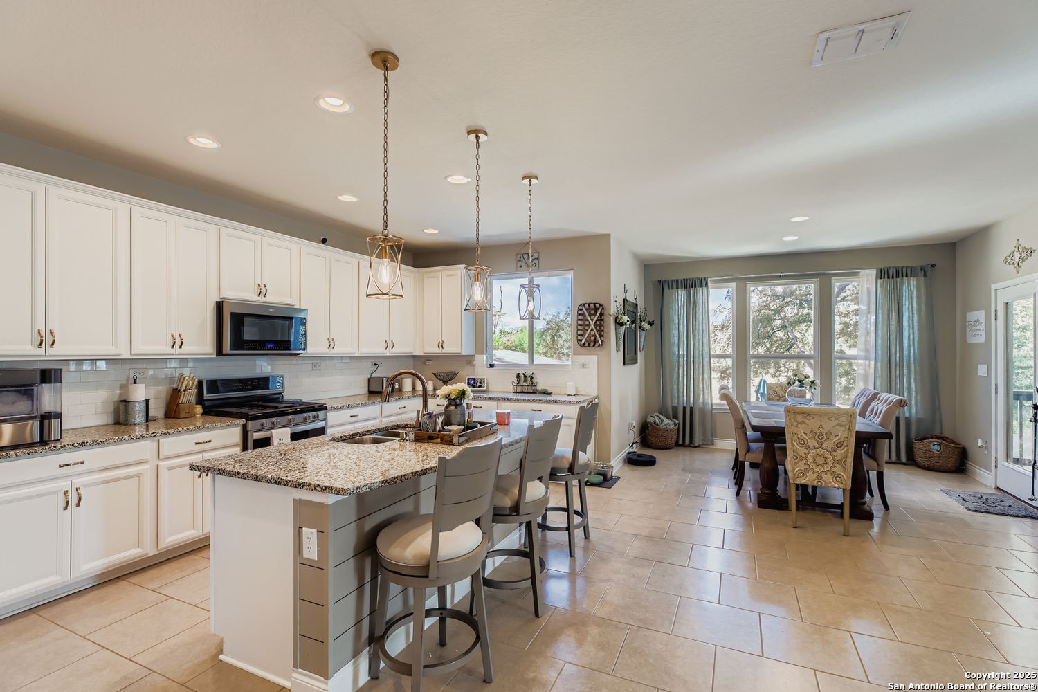 10639 Hibiscus Cove Helotes, TX 78023 - Photo 16 of 34 a kitchen with stainless steel appliances kitchen island granite countertop a sink a stove a dining table and chairs