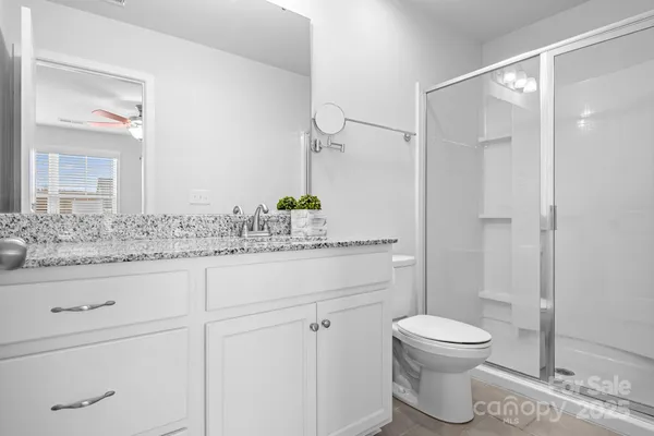 a bathroom with a granite countertop sink a toilet and a shower