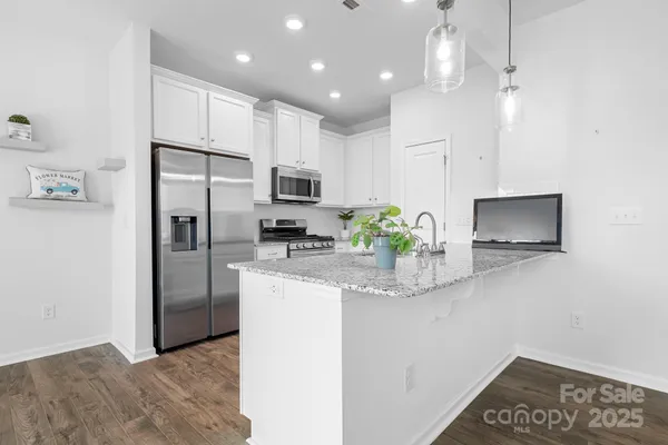 a kitchen with kitchen island granite countertop a refrigerator a sink a stove a microwave a counter space and cabinets