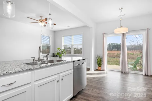 a view of a kitchen from a center island wooden floor and a chandelier