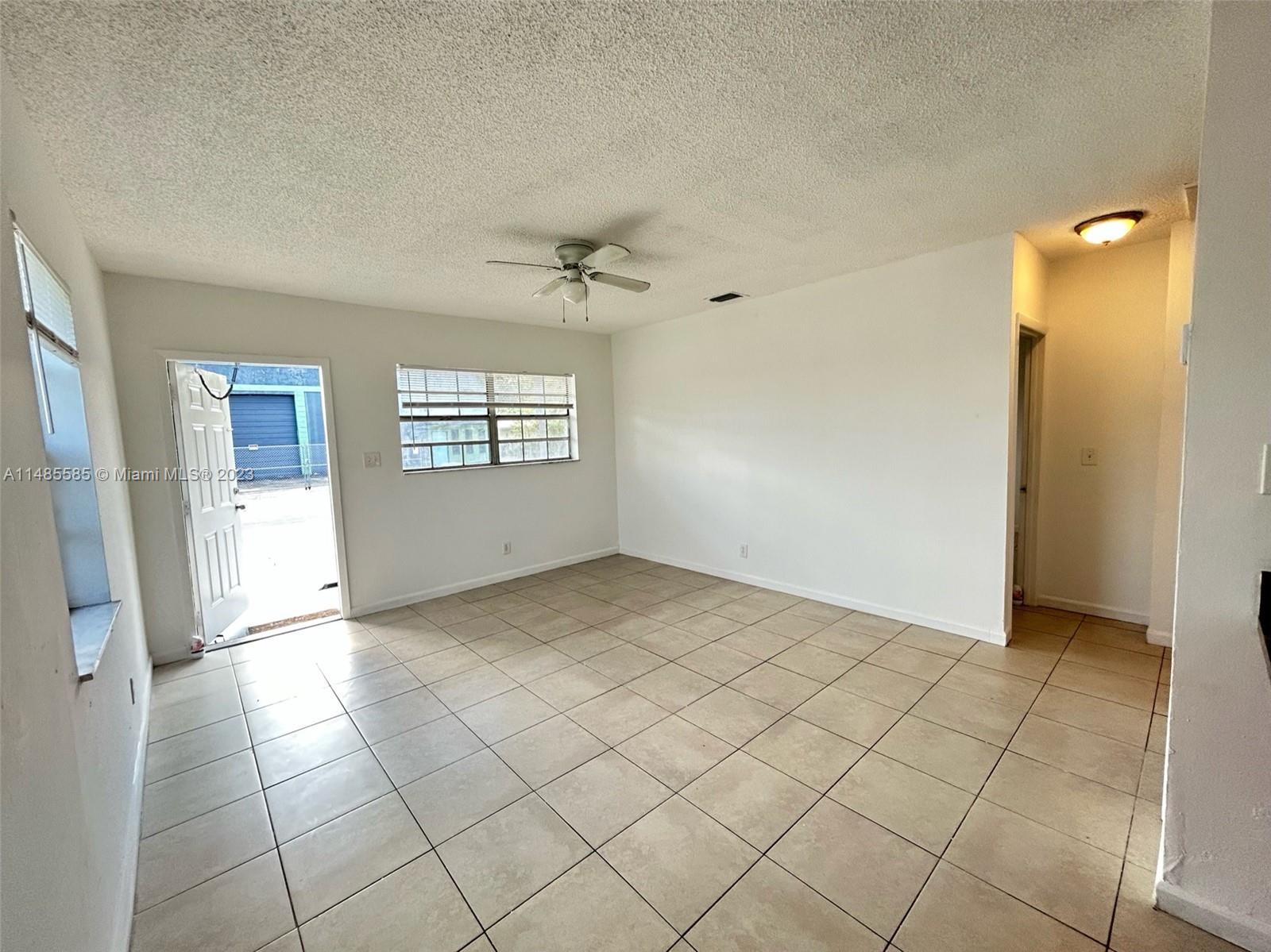 990 Phippen Waiters Road, Unit 1 Dania Beach, FL 33004 - Photo 2 of 8 a view of an empty room with window and chandelier fan