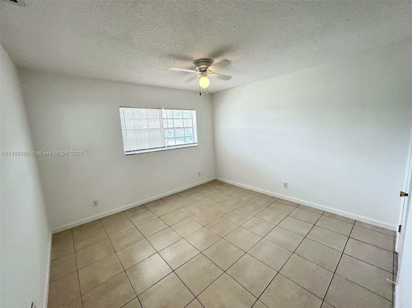 990 Phippen Waiters Road, Unit 1 Dania Beach, FL 33004 - Photo 6 of 8 an empty room with windows and ceiling fan