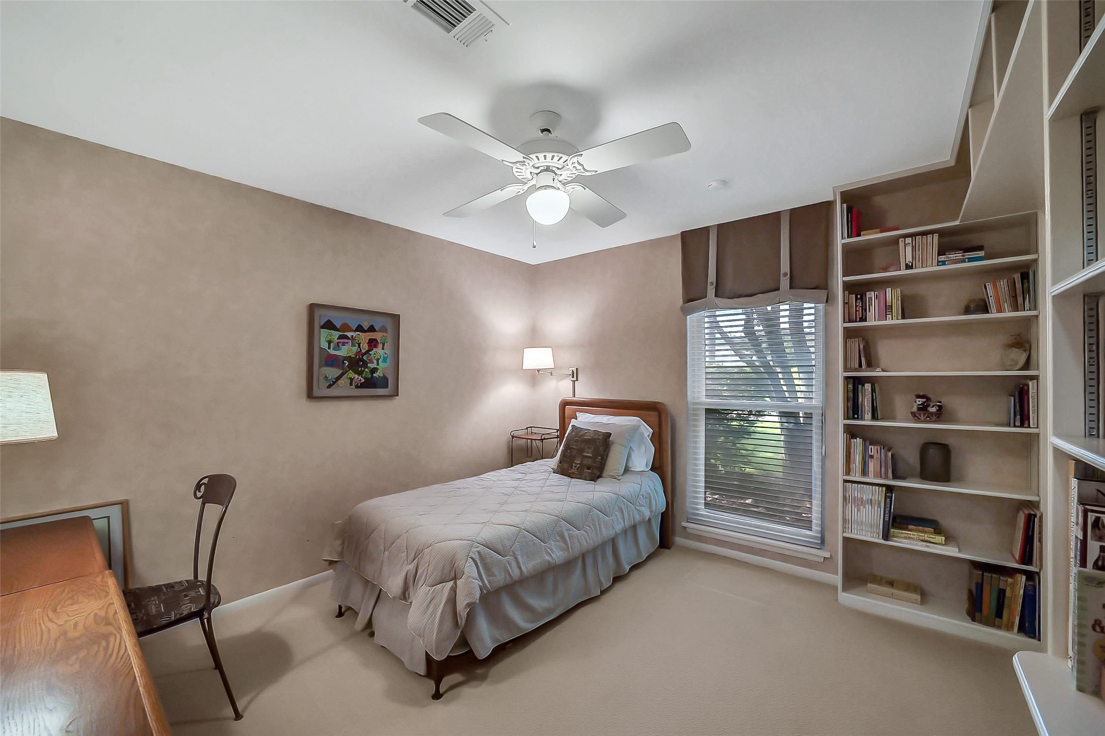 5626 Hummingbird Street Houston, TX 77096 - Photo 24 of 34 Along the bedroom wing hallway, there are also two additional bedrooms and a fully renovated hall bath. This is one of the comfortable bedrooms with neutral coloring and carpeting. Built-in bookcases create interest and provide great display or additional storage. There is also excellent closet storage. This room views out to the front yard area.