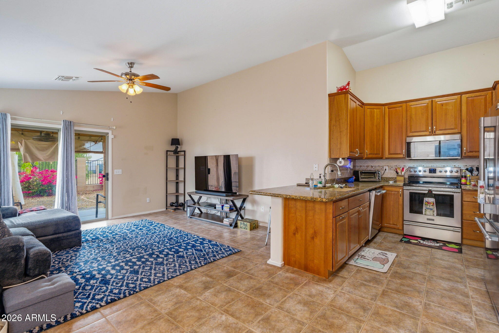 15843 West Washington Street Goodyear, AZ 85338 - Photo 11 of 39 a kitchen with stainless steel appliances granite countertop a stove top oven a sink dishwasher a dining table and chairs with wooden floor