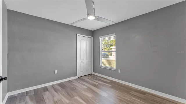 an empty room with wooden floor and ceiling fan