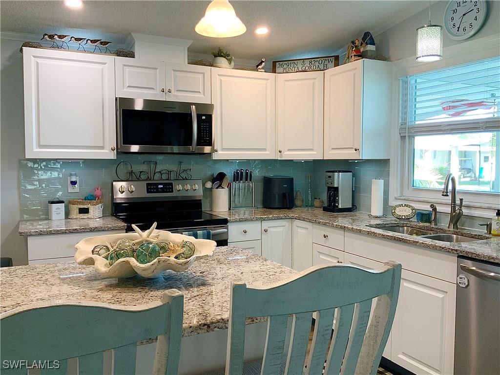 15550 Burnt Store Road, Unit 86 Punta Gorda, FL 33955 - Photo 11 of 36 a kitchen with stainless steel appliances granite countertop a sink a stove top oven a chimney and cabinets