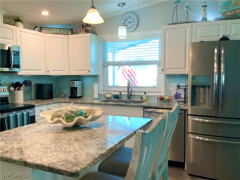15550 Burnt Store Road, Unit 86 Punta Gorda, FL 33955 - Photo 12 of 36 a kitchen with stainless steel appliances granite countertop a sink refrigerator and microwave