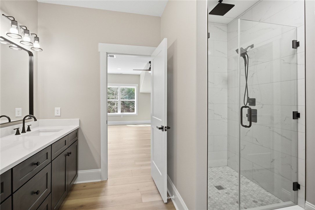 147 McAlister Road West Union, SC 29696 - Photo 30 of 49 This upstairs shared bathroom features a double vanity and a glass-enclosed shower with contemporary fixtures.