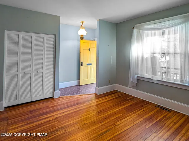 a view of empty room with wooden floor and fan