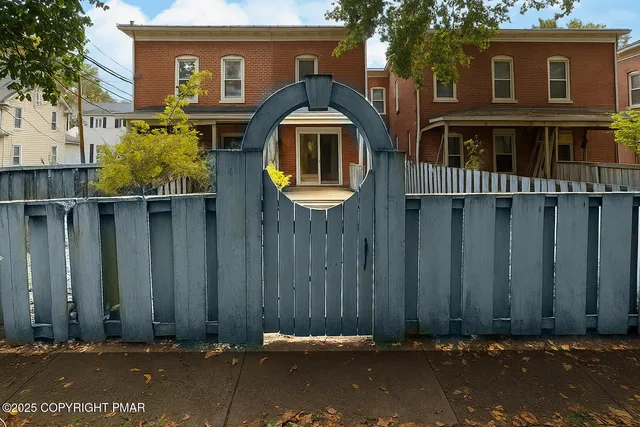 a front view of a house with a door and tree
