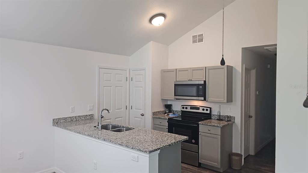 15028 Southwest 24th Place Ocala, FL 34481 - Photo 4 of 25 a kitchen with granite countertop a stove and a refrigerator