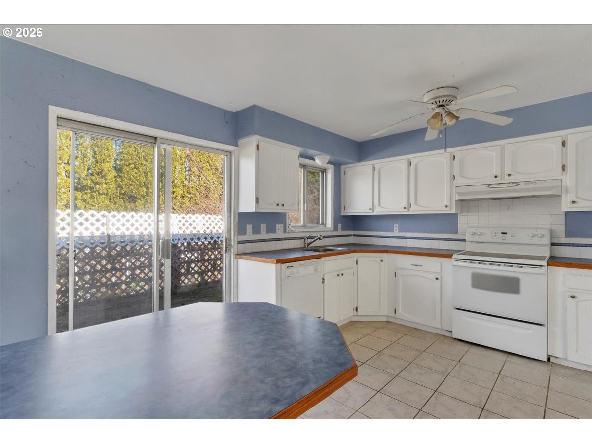 1645 Southwest 27th Street Gresham, OR 97080 - Photo 11 of 48 a kitchen with granite countertop a stove a sink dishwasher and white cabinets with wooden floor
