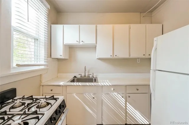 a kitchen with a white cabinets sink and white stainless steel appliances