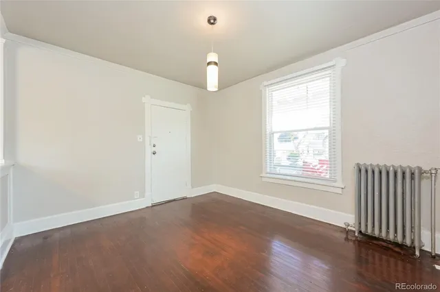 an empty room with wooden floor chandelier fan and windows