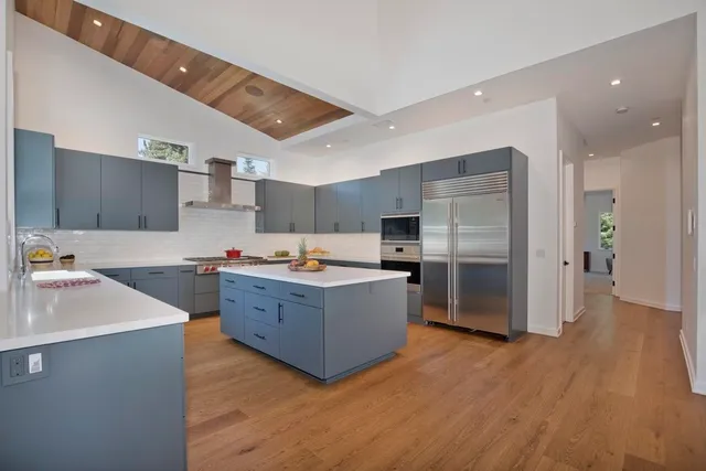 a large kitchen with stainless steel appliances a sink a refrigerator and a stove