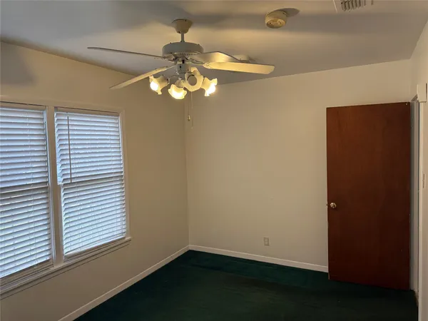 en empty room with windows and chandelier fan