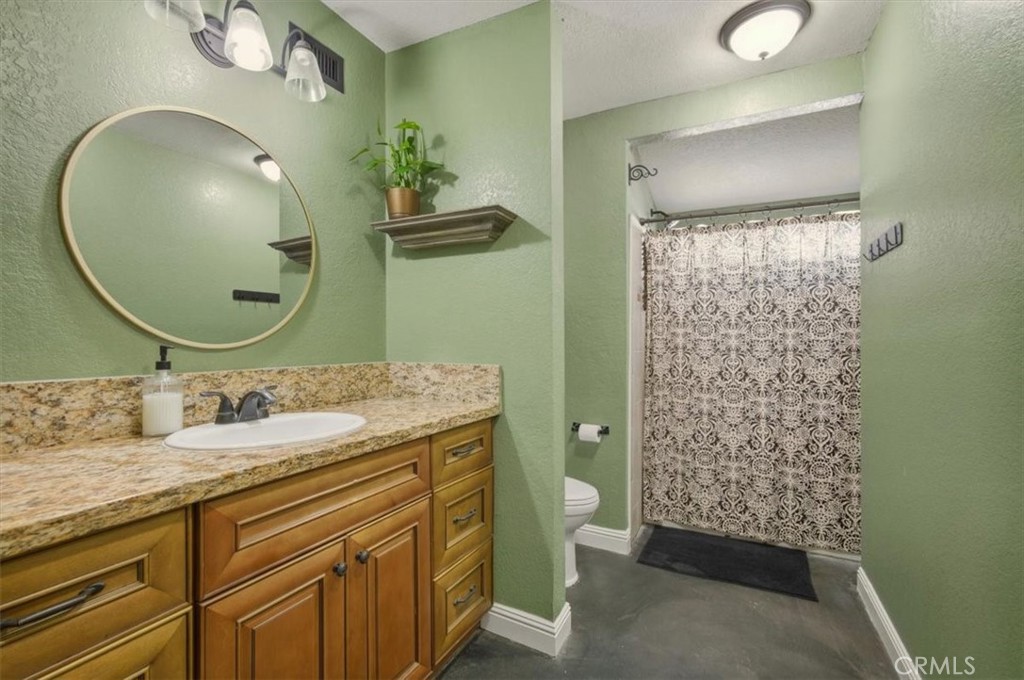 3495 Mono Drive Riverside, CA 92506 - Photo 16 of 34 a bathroom with a granite countertop sink a toilet and a mirror