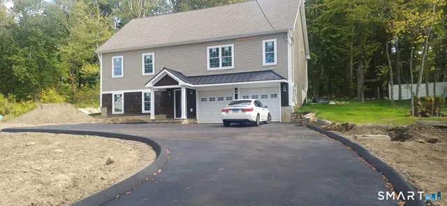 a front view of a house with a garden and trees