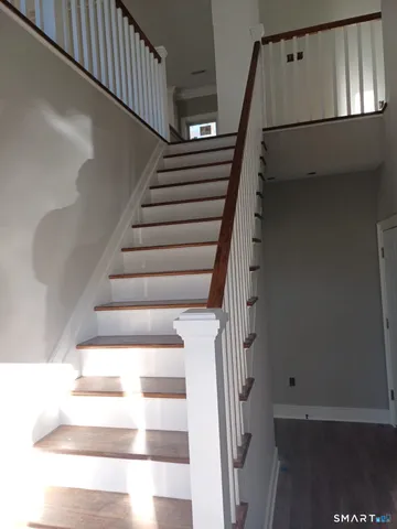 a kitchen with stainless steel appliances granite countertop a refrigerator a sink dishwasher a stove and a dining table with wooden floor