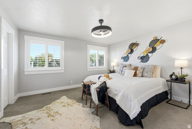 1405 Vintry Lane Murray, UT 84121 - Photo 16 of 44 Spacious room featuring carpeting, two windows with white plantation shutters, and a modern ceiling fan with integrated lighting