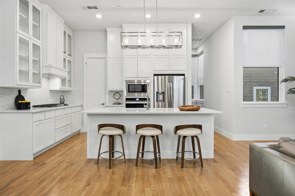 625 North Tyler Street, Unit 402 Dallas, TX 75208 - Photo 14 of 31 a white kitchen with stainless steel appliances granite countertop a stove a sink a refrigerator and white cabinets with wooden floor