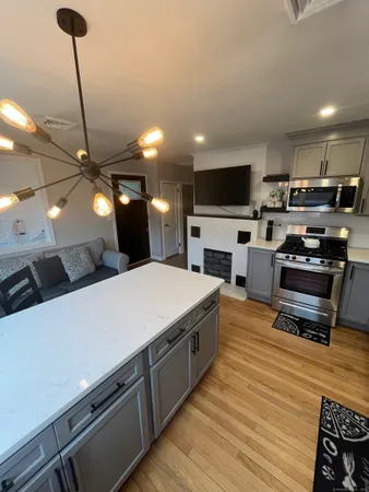 a large kitchen with stainless steel appliances a stove a sink dishwasher a refrigerator white cabinets and wooden floor