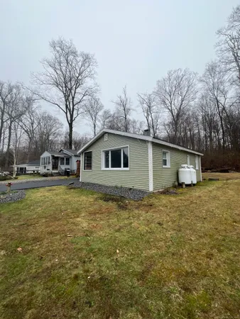 a front view of house with yard and trees in the background