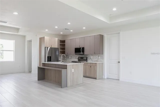 a large white kitchen with stainless steel appliances granite countertop a stove and a sink