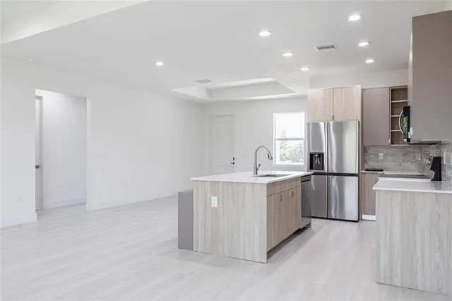 a kitchen with stainless steel appliances a sink a stove a refrigerator and white cabinets