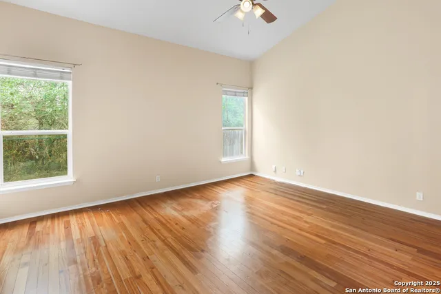 a view of a room with wooden floor and a ceiling fan