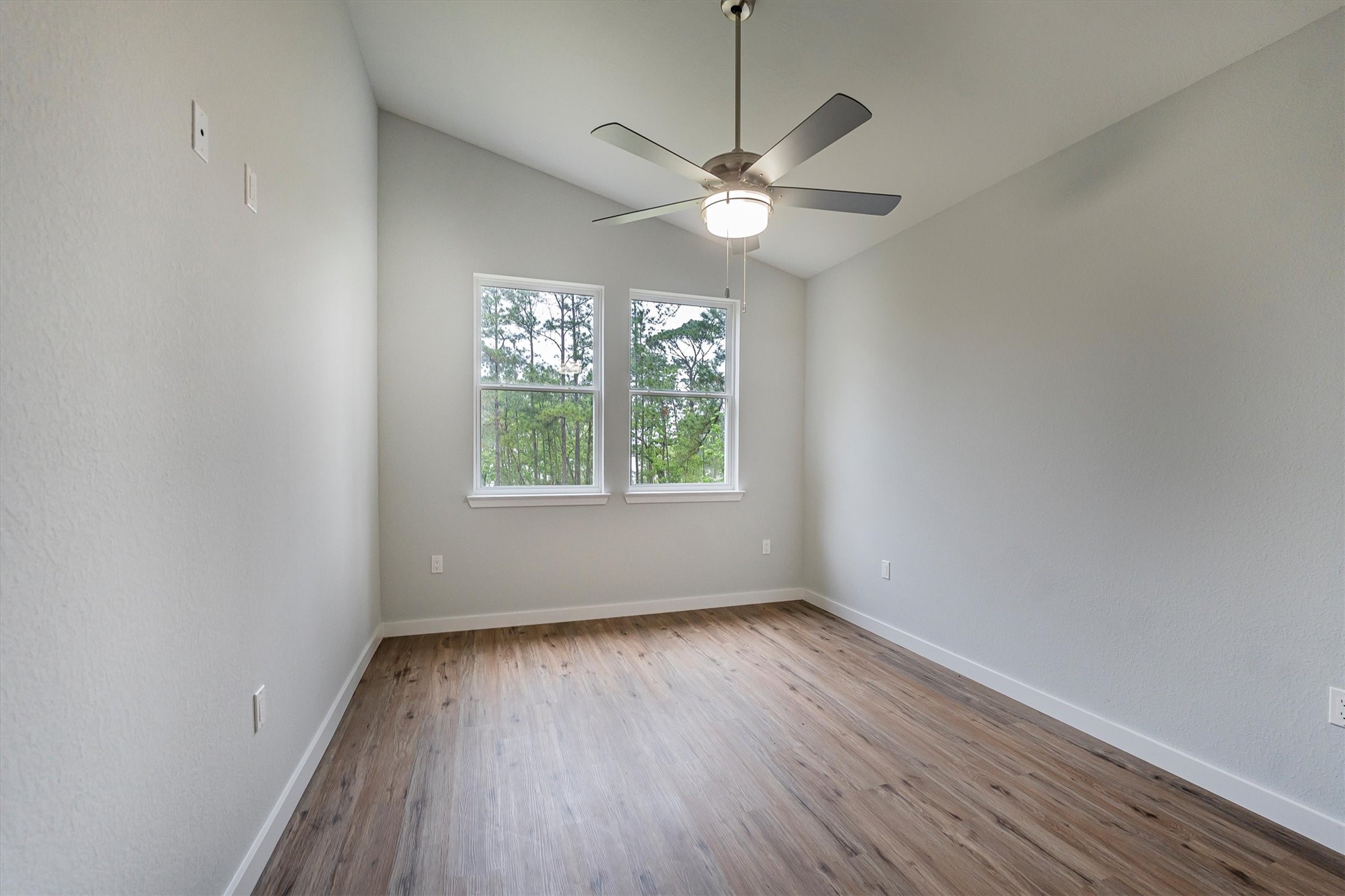24411 Oakaland Hls Road Point Blank, TX 77364 - Photo 19 of 40 an empty room with wooden floor fan and windows