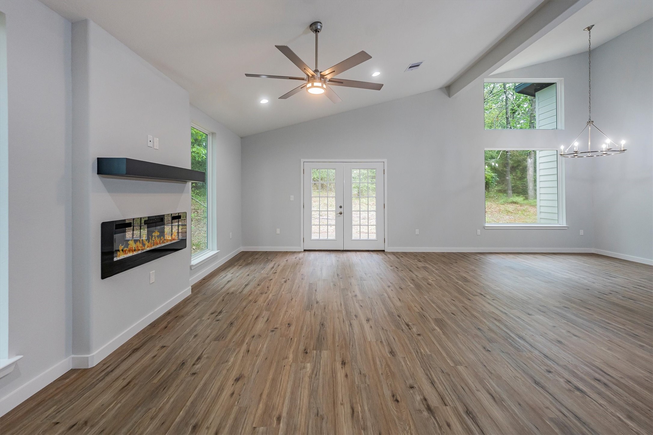 24411 Oakaland Hls Road Point Blank, TX 77364 - Photo 6 of 40 an empty room with wooden floor a ceiling fan and windows