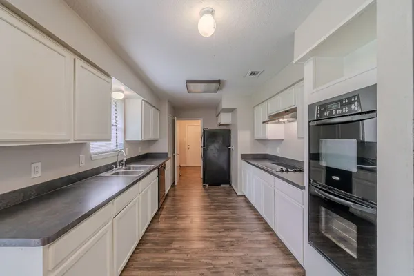 a large kitchen with stainless steel appliances granite countertop a stove a sink and a refrigerator